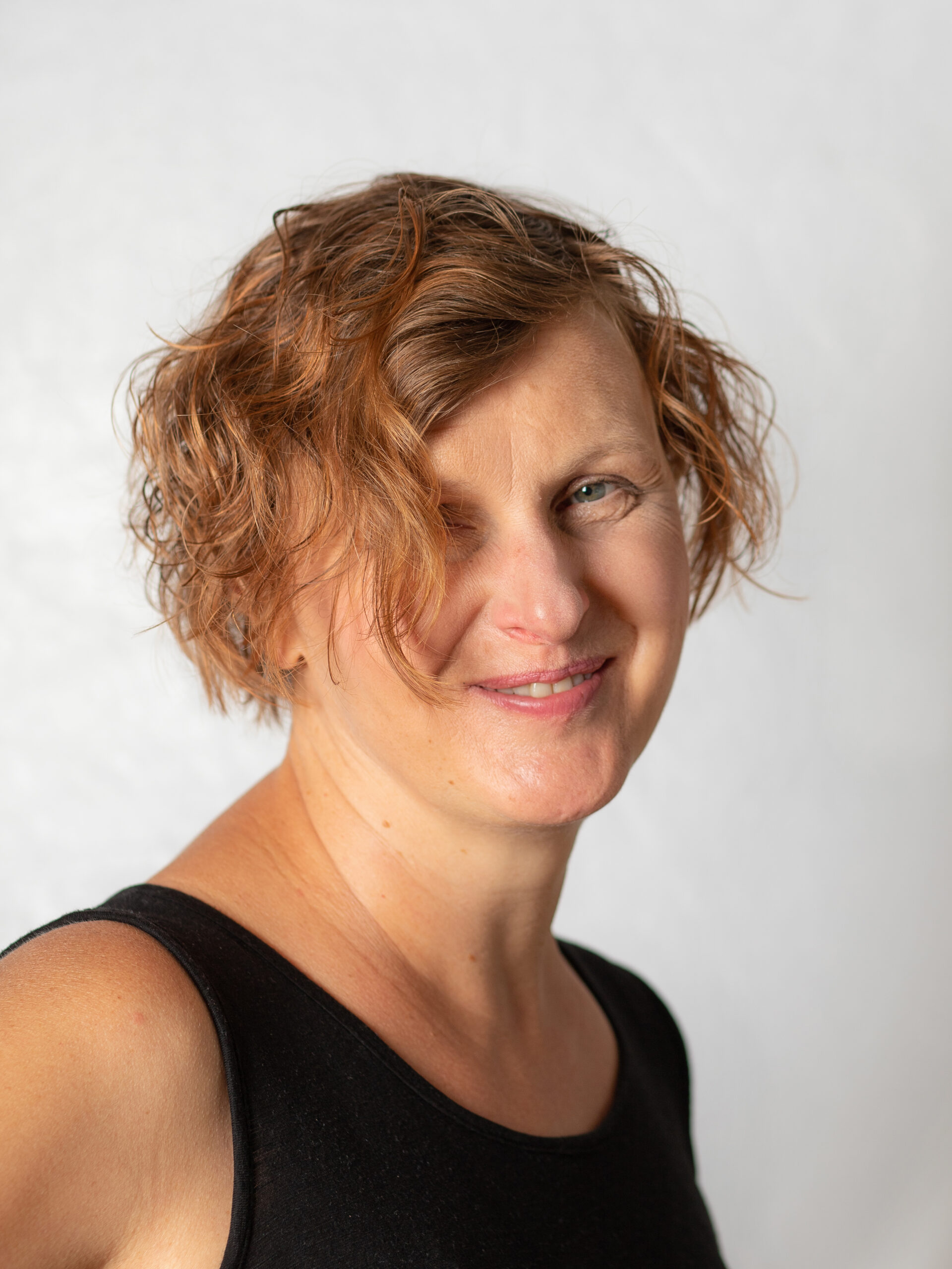 Lächelnde Frau mit kurzem, lockigem Haar.