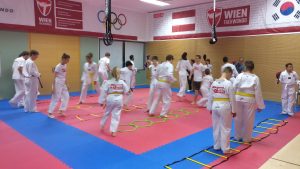 Menschen in weißen Sportanzügen auf Matten, die trainieren.