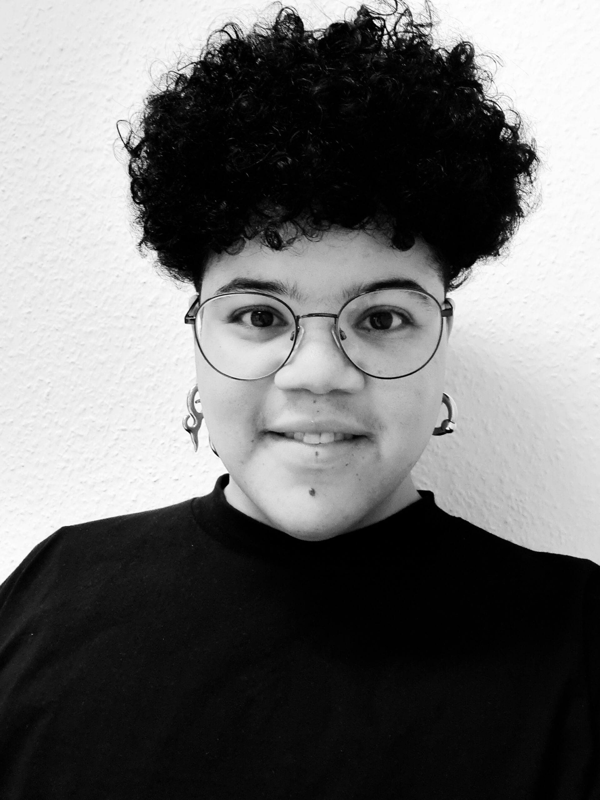 Person mit kurzem dunklem Haar und Brille.