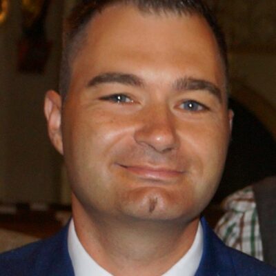 Lächelnder Mann mit kurzem, dunklem Haar.