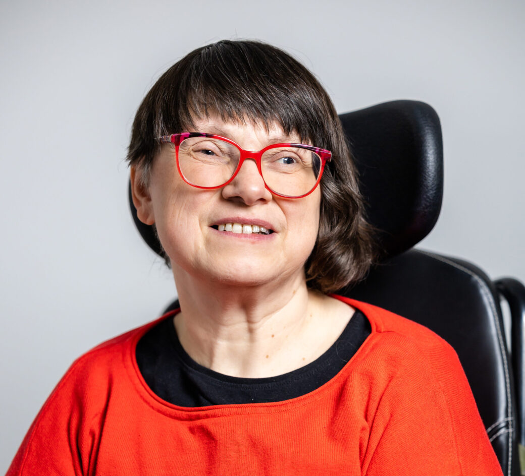Foto zeigt Frau mit dunklem Haar, die in die Kamera lächelt.