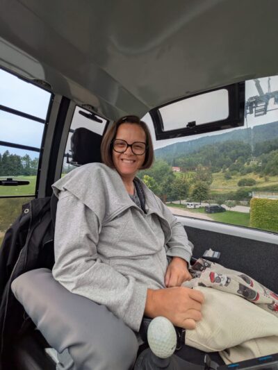 Frau sitzt in Seilbahn. Sie hat halblange, braune Haare.