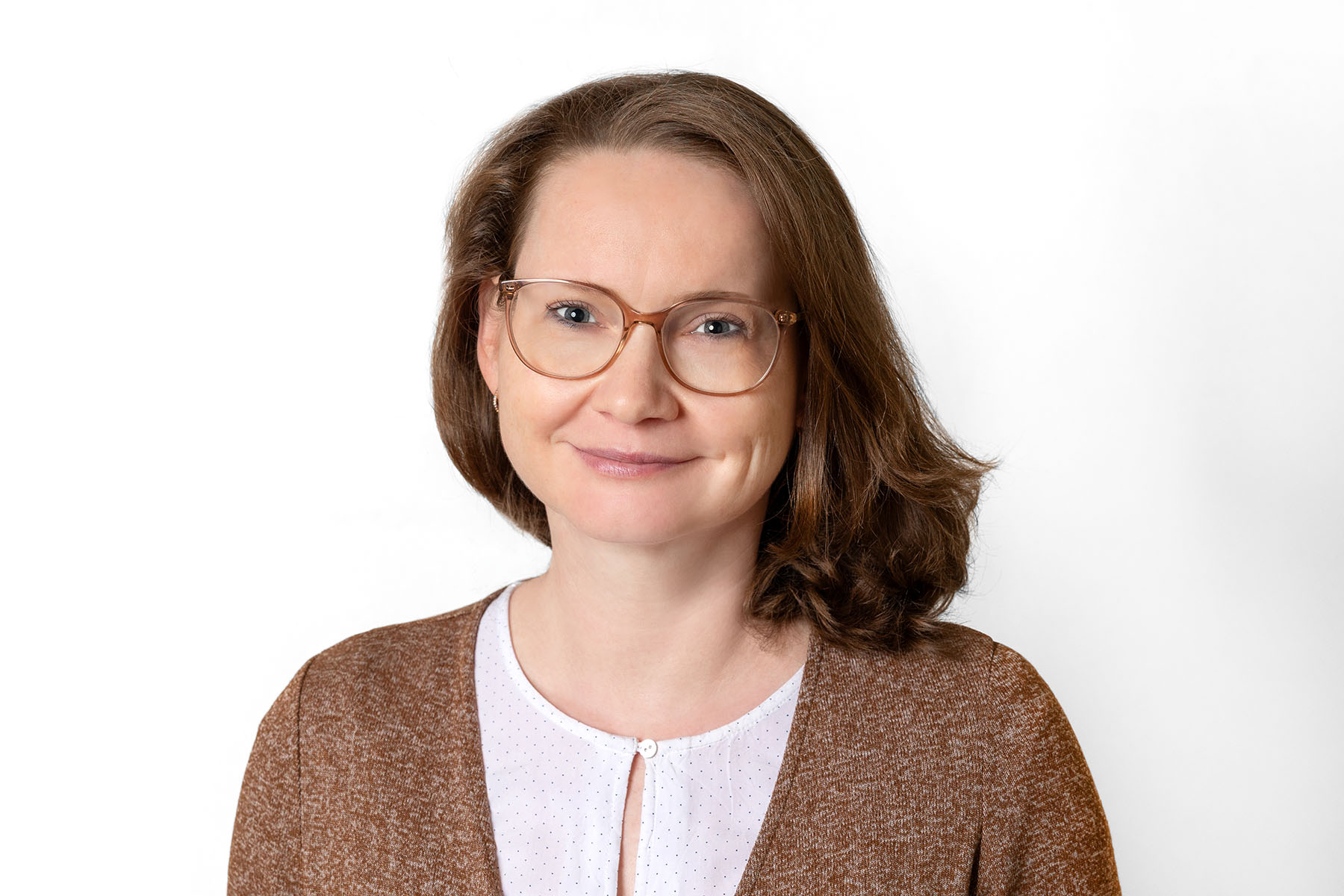 Frau mit schulterlangem braunen Haar und Brille schaut in die Kamera.