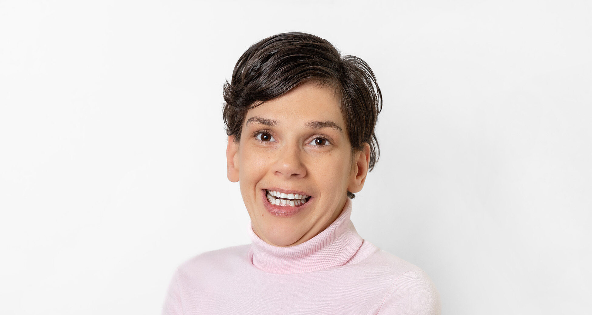 Frau mit kurzem, braunem Haar lächelt in die Kamera.