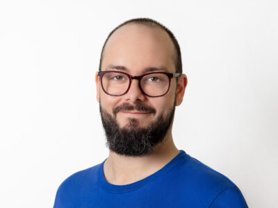 Mann mit Bart und Brille trägt ein blaues T-Shirt