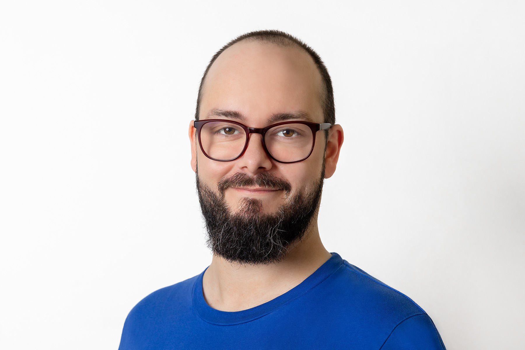 Mann mit Bart und Brille trägt ein blaues T-Shirt