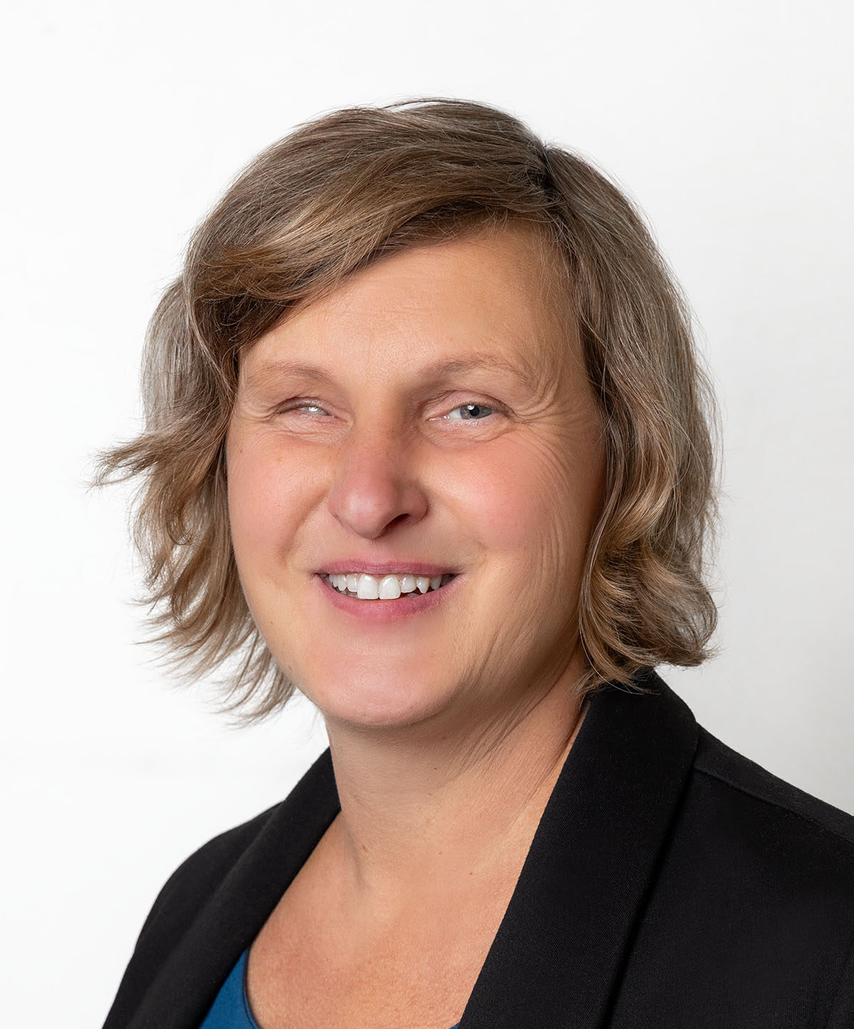 Frau mit brünettem, schulterlangen Haar lächelt in die Kamera