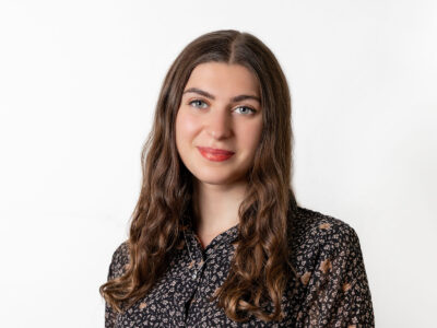 Frau mit braunem langen Haar trägt eine geblümte Bluse