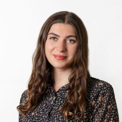 Frau mit braunem langen Haar trägt eine geblümte Bluse