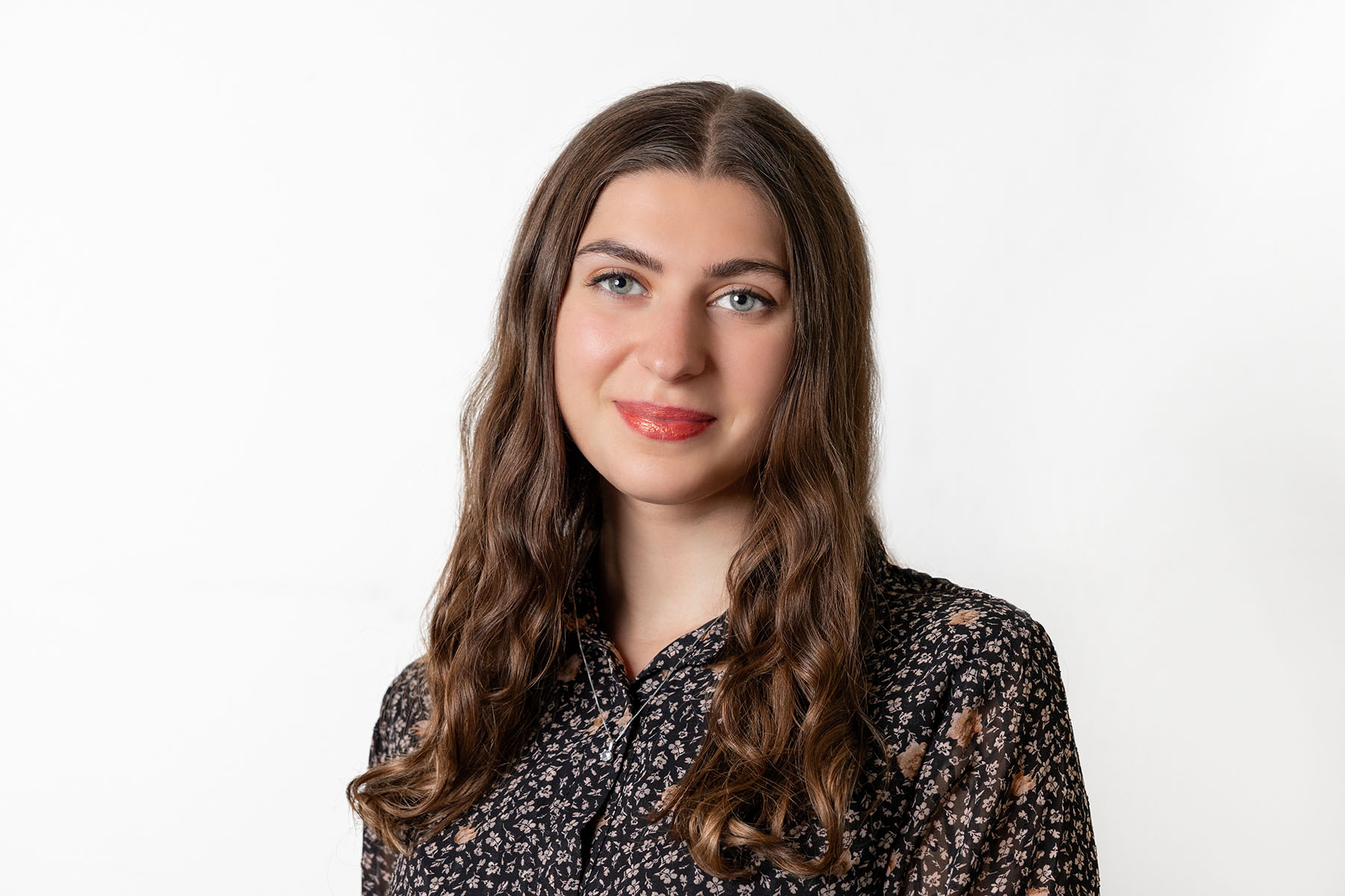 Frau mit braunem langen Haar trägt eine geblümte Bluse